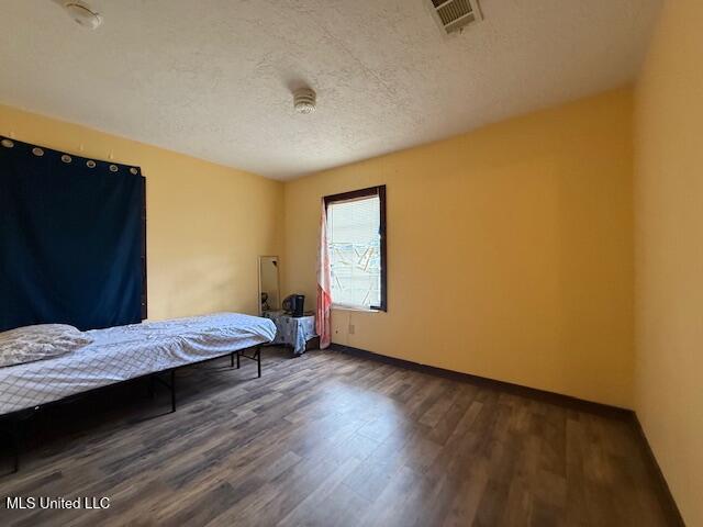 bedroom featuring dark hardwood / wood-style floors and a textured ceiling