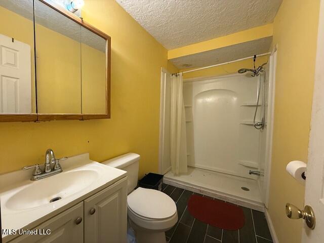 bathroom featuring vanity, toilet, a shower with shower curtain, and a textured ceiling