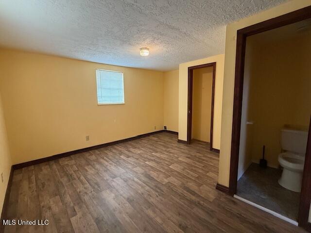 unfurnished bedroom with dark hardwood / wood-style floors and a textured ceiling