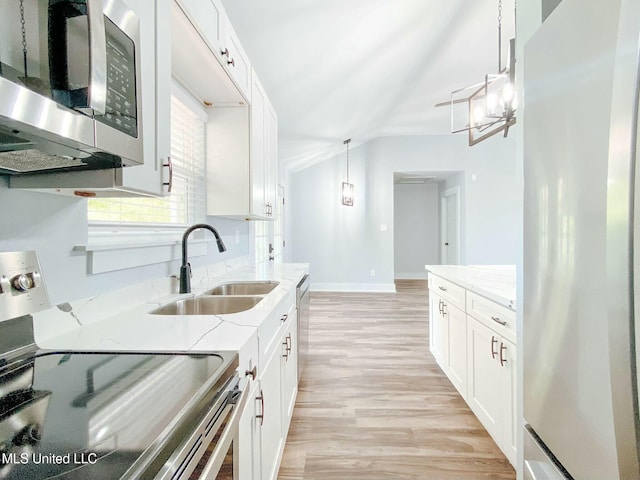 kitchen with sink, hanging light fixtures, stainless steel appliances, light stone countertops, and white cabinets