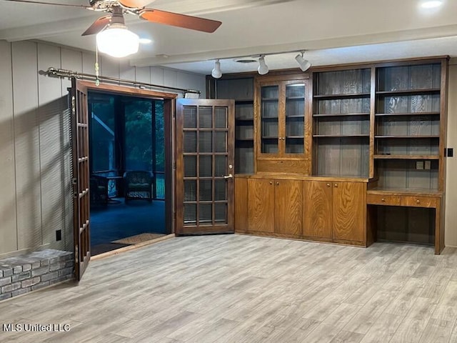 unfurnished living room with ceiling fan, beam ceiling, and light wood-type flooring