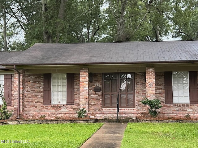 entrance to property with covered porch and a lawn