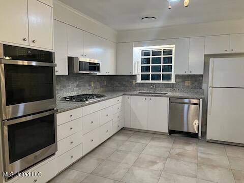 kitchen with decorative backsplash, white cabinets, stainless steel appliances, and sink