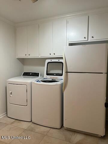 clothes washing area with cabinets, washing machine and dryer, and light tile patterned floors