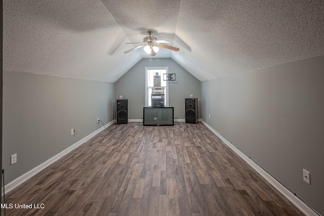 additional living space featuring dark hardwood / wood-style flooring, lofted ceiling, a textured ceiling, and ceiling fan