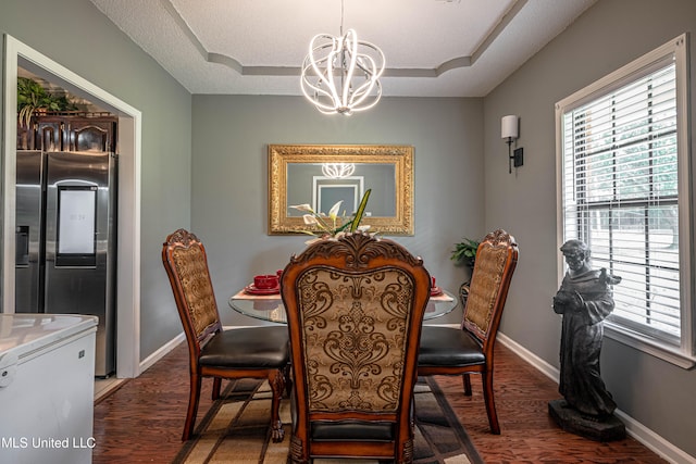 dining room with dark wood-type flooring, a textured ceiling, and a notable chandelier