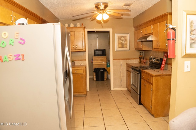 kitchen featuring tile countertops, light tile patterned flooring, black appliances, and a textured ceiling