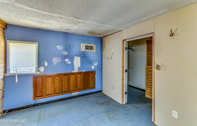 interior space with a wall mounted air conditioner and a textured ceiling