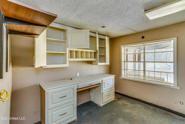 unfurnished office with a textured ceiling, concrete floors, and baseboards