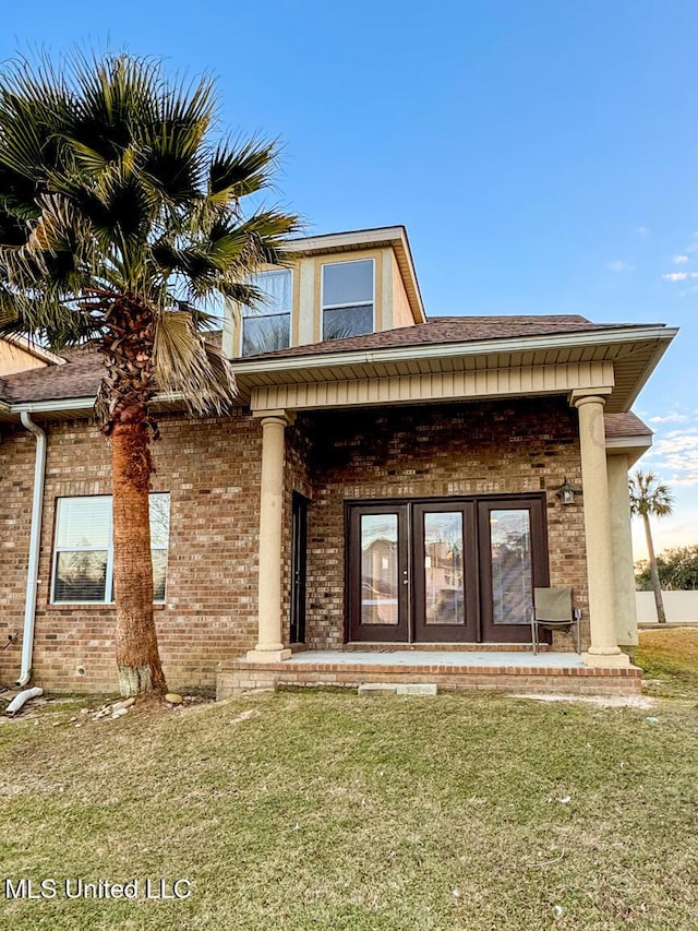 doorway to property featuring french doors and a lawn