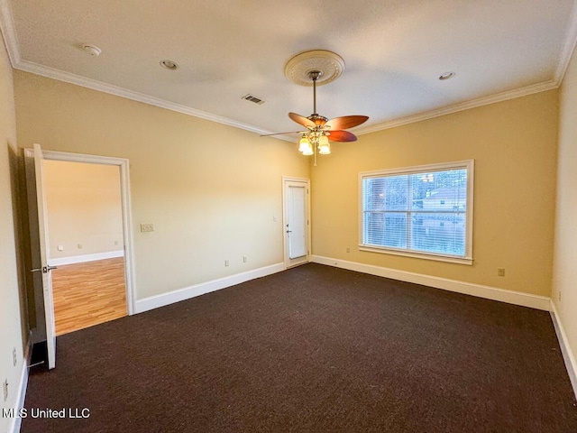 empty room featuring crown molding, dark colored carpet, and ceiling fan