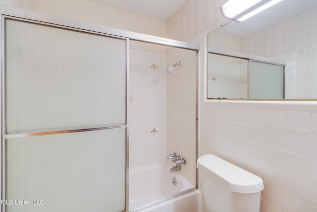 820 Lackland Dr, Biloxi, MS 39532 - full bathroom featuring toilet, bath / shower combo with glass door, wallpapered walls, and tile walls