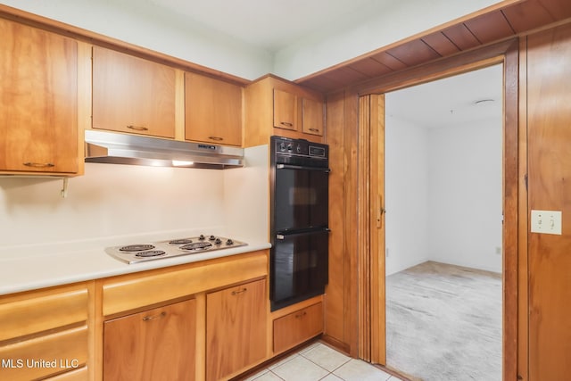 820 Lackland Dr, Biloxi, MS 39532 - kitchen with under cabinet range hood, stovetop, light countertops, light colored carpet, and light tile patterned floors