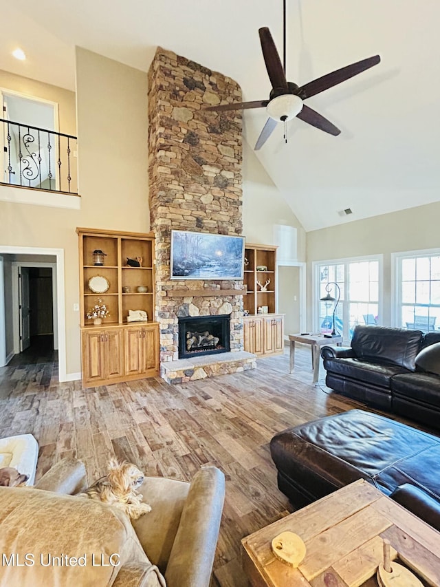 living room with ceiling fan, high vaulted ceiling, a fireplace, and hardwood / wood-style floors