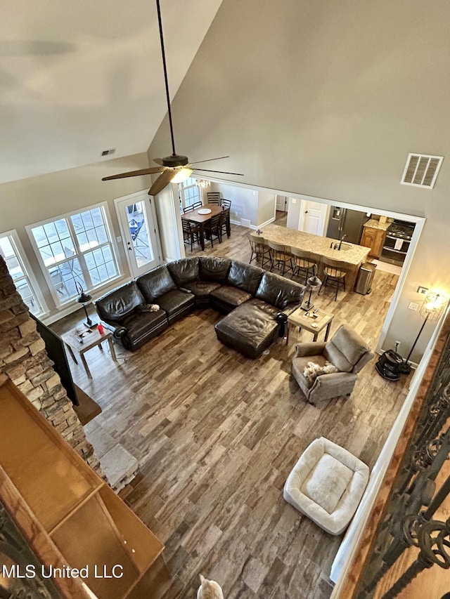 living room with wood-type flooring, ceiling fan, and high vaulted ceiling