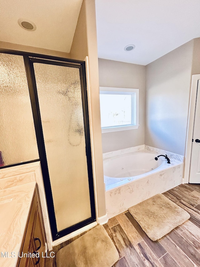 bathroom featuring wood-type flooring, shower with separate bathtub, and vanity