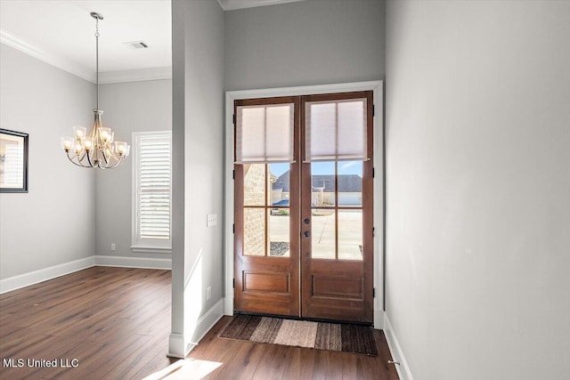 doorway featuring crown molding, plenty of natural light, dark wood-type flooring, and an inviting chandelier