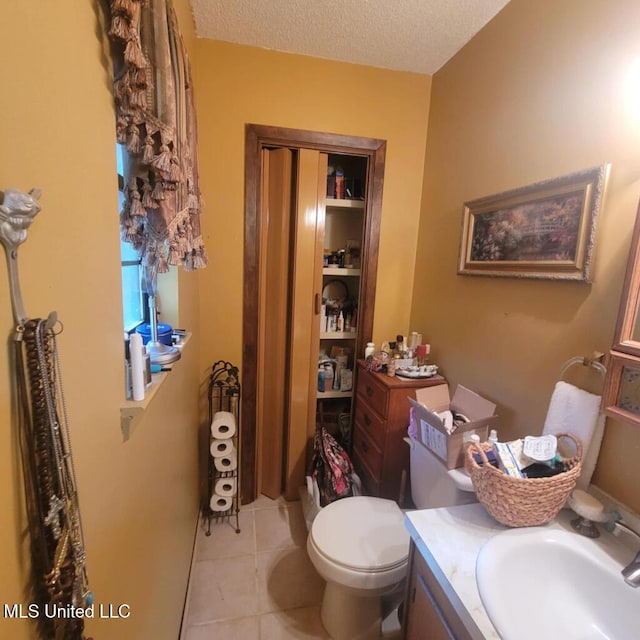 bathroom featuring tile patterned flooring, vanity, toilet, and a textured ceiling