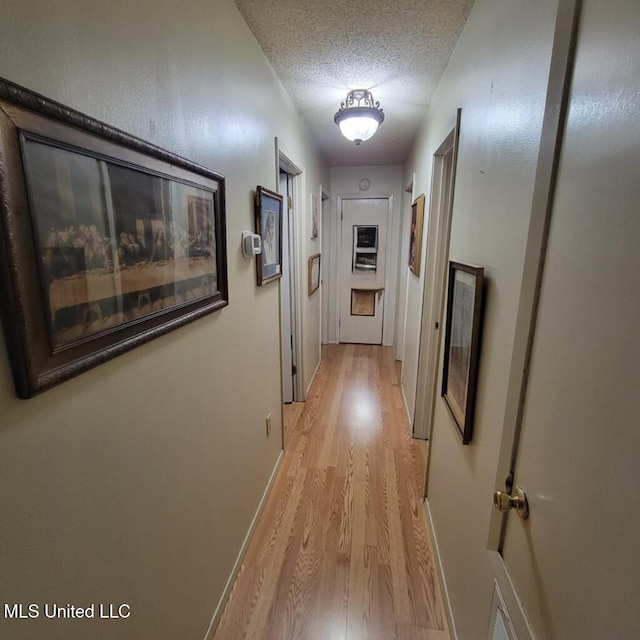 hallway featuring a textured ceiling and light wood-type flooring