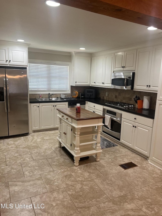 kitchen with wood counters, sink, white cabinetry, appliances with stainless steel finishes, and tasteful backsplash