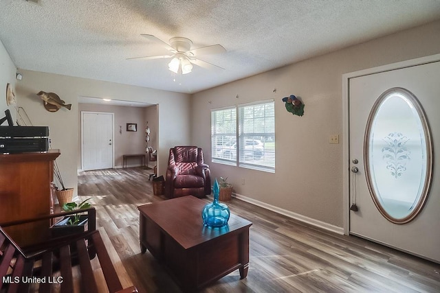 living room featuring a textured ceiling, wood-type flooring, and ceiling fan