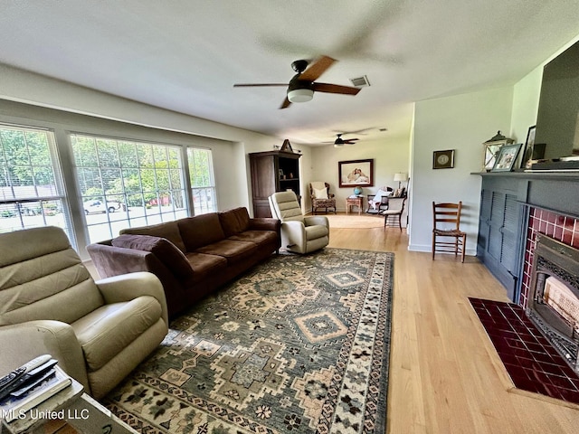 308 College St, Carthage, MS 39051 - living room with visible vents, light wood-style flooring, a brick fireplace, and ceiling fan