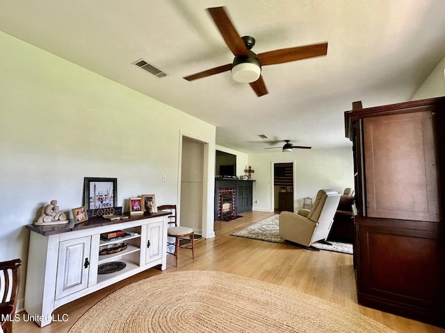 308 College St, Carthage, MS 39051 - living area with visible vents, a ceiling fan, light wood finished floors, and a fireplace