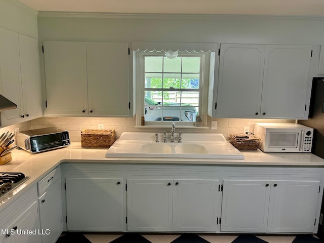 308 College St, Carthage, MS 39051 - kitchen with white cabinets, crown molding, tasteful backsplash, and white microwave