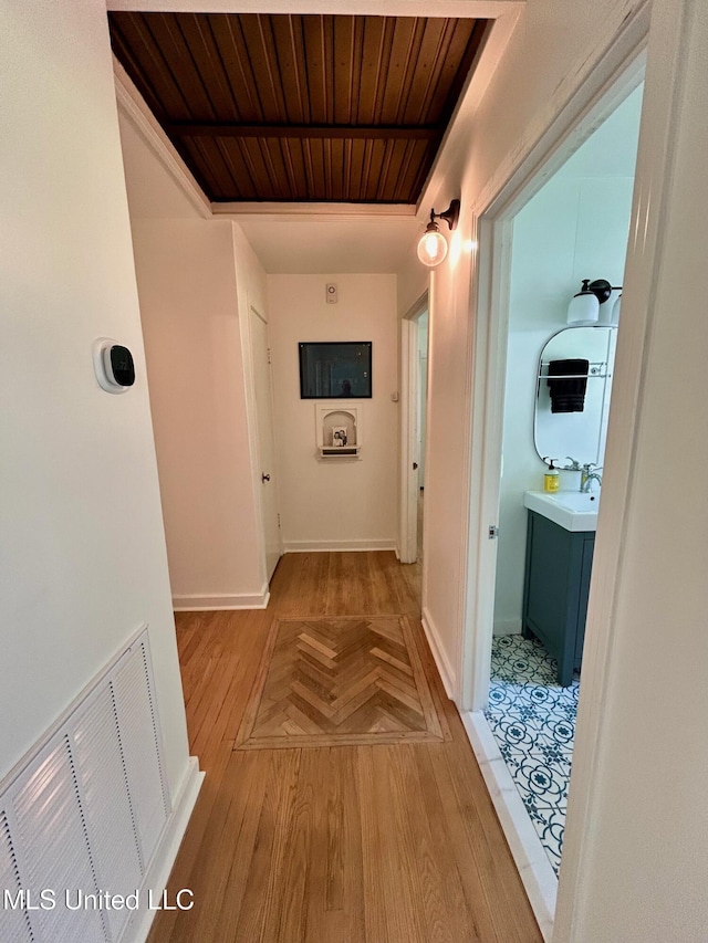 308 College St, Carthage, MS 39051 - hallway featuring visible vents, baseboards, wooden ceiling, a sink, and light wood finished floors
