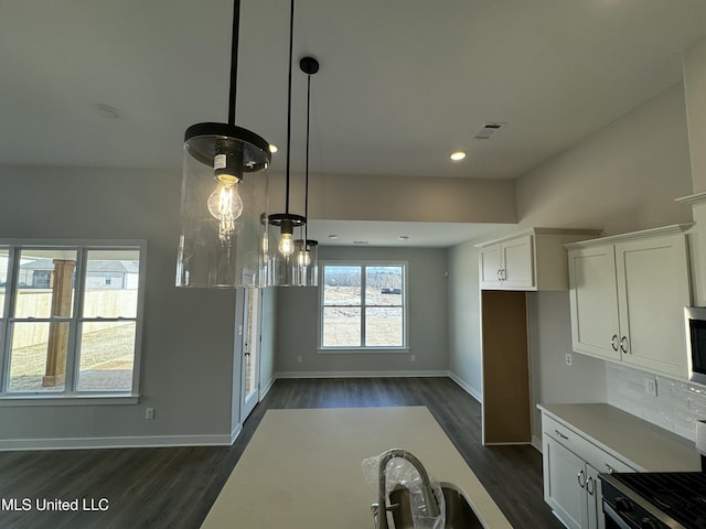 kitchen with pendant lighting, white cabinets, dark hardwood / wood-style floors, and stainless steel appliances