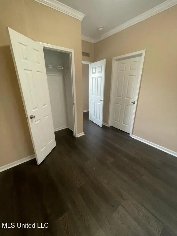 12205 Prudie Cir, Gulfport, MS 39503 - unfurnished bedroom featuring crown molding, baseboards, dark wood-style flooring, and a closet