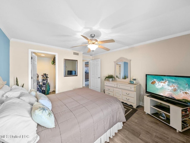 bedroom with hardwood / wood-style floors, ornamental molding, a spacious closet, ceiling fan, and a closet