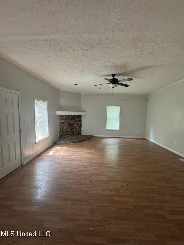 941 Dorgan St, Jackson, MS 39204 - unfurnished living room with plenty of natural light, wood finished floors, a stone fireplace, a textured ceiling, and a ceiling fan