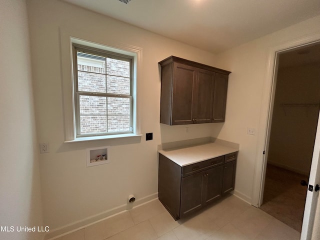 clothes washing area featuring hookup for a washing machine, light tile patterned flooring, and cabinets