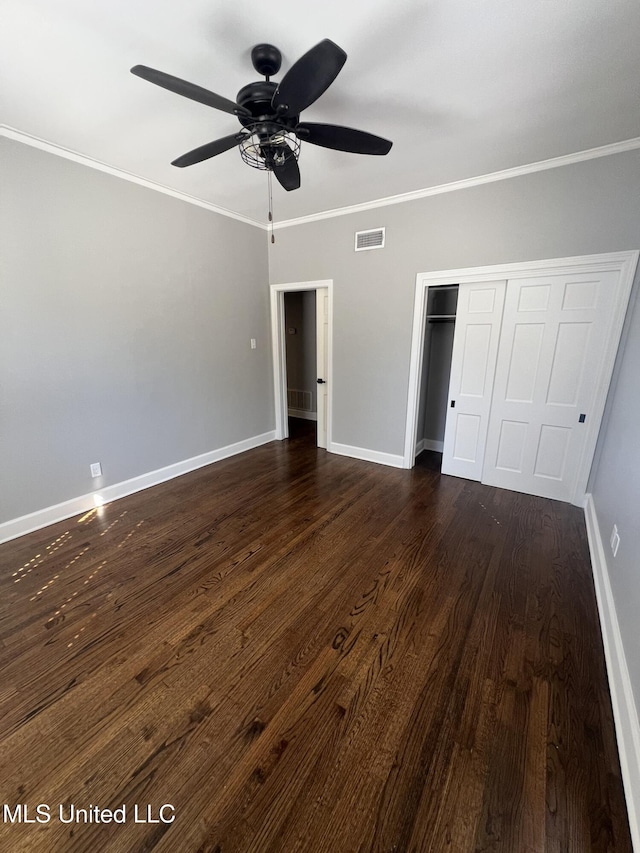 unfurnished bedroom featuring baseboards, visible vents, ornamental molding, dark wood-style flooring, and a closet