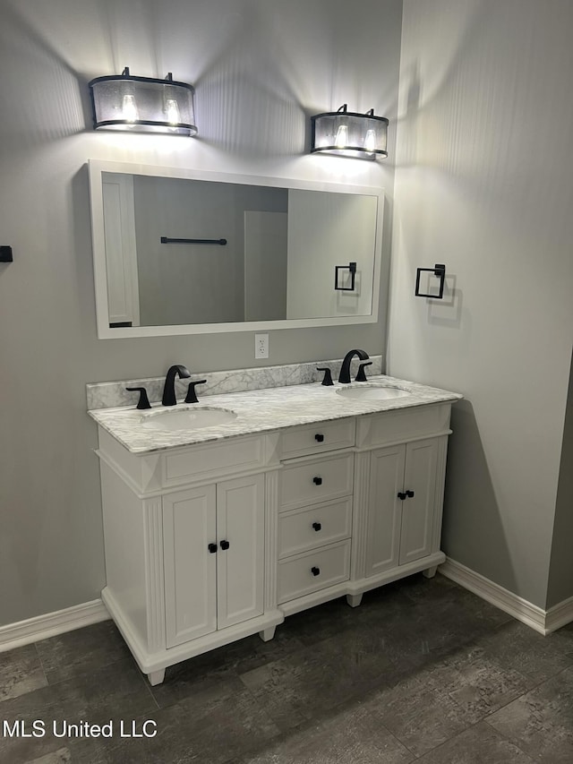 bathroom featuring double vanity, a sink, and baseboards