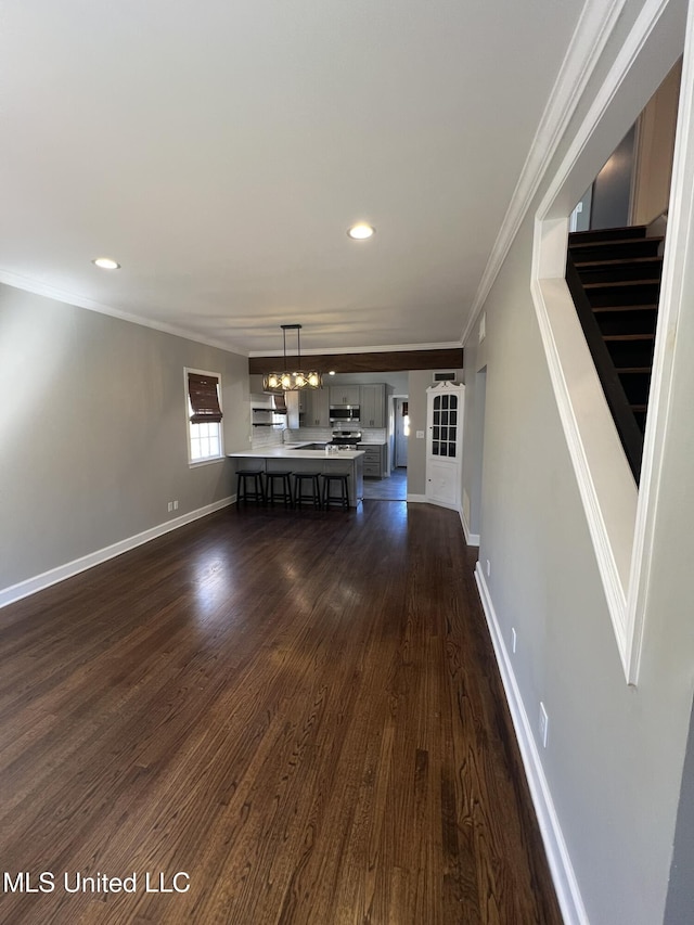 unfurnished living room featuring dark wood-style flooring, a notable chandelier, stairway, ornamental molding, and baseboards