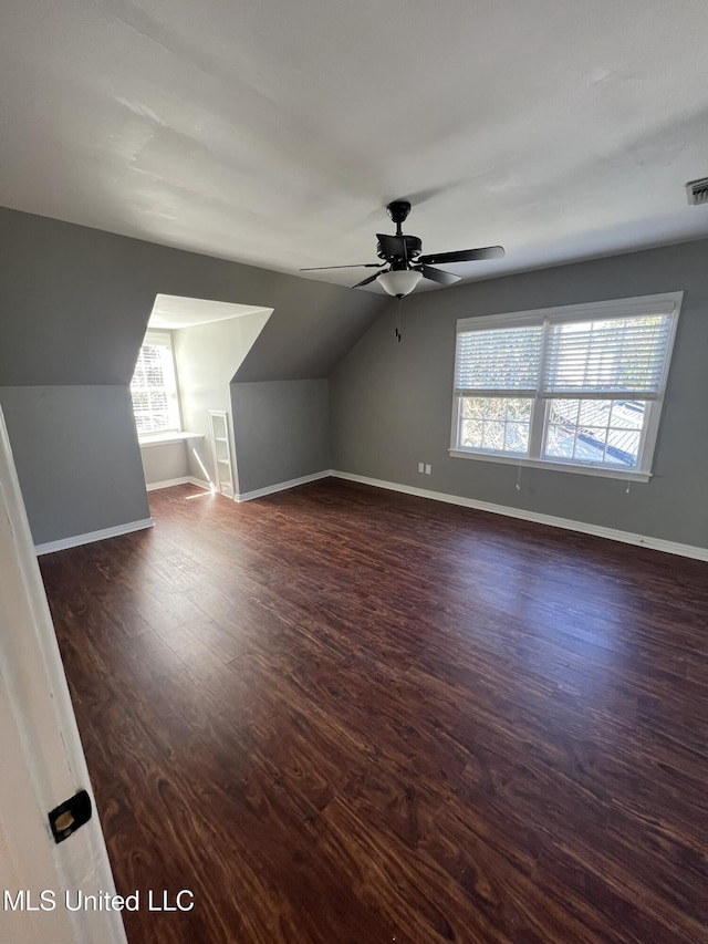 additional living space featuring dark wood-style floors, lofted ceiling, visible vents, a ceiling fan, and baseboards