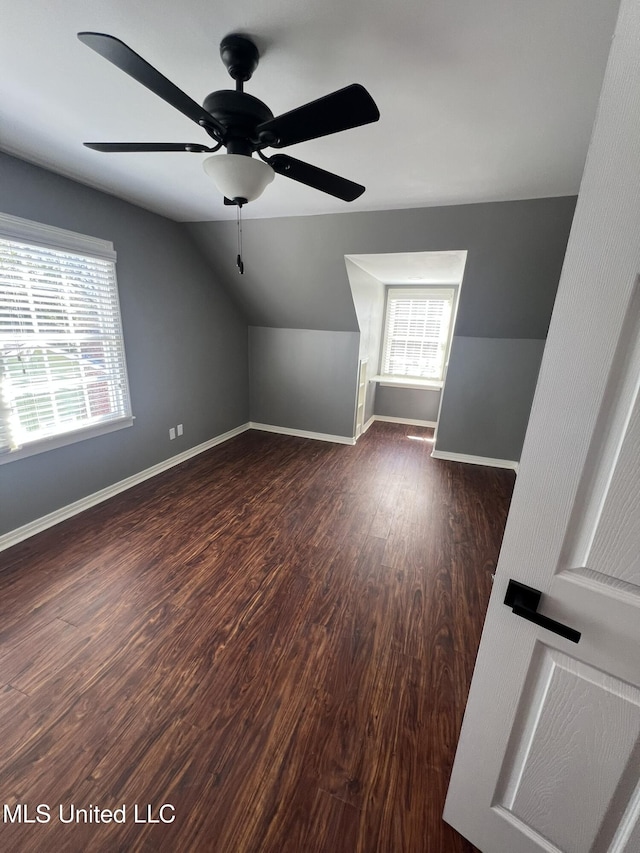 additional living space with vaulted ceiling, dark wood-style flooring, a wealth of natural light, and baseboards