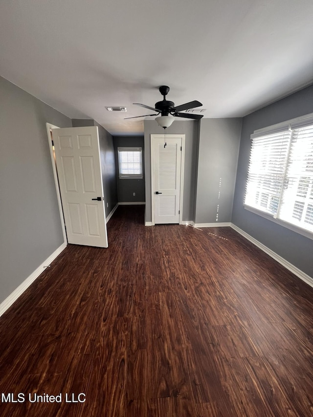 unfurnished bedroom with dark wood-type flooring, visible vents, ceiling fan, and baseboards