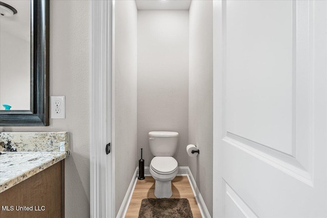 bathroom with wood finished floors, vanity, toilet, and baseboards