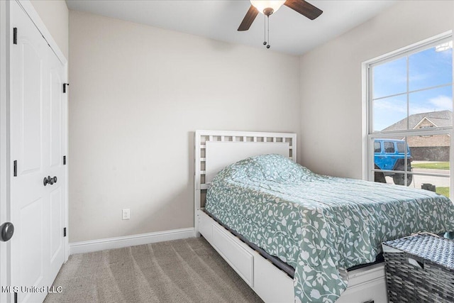 bedroom featuring baseboards, light colored carpet, and a ceiling fan