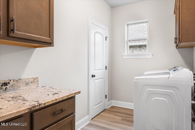laundry room with cabinet space, light wood-style floors, baseboards, and independent washer and dryer
