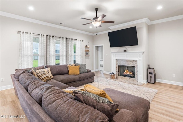 living area with a ceiling fan, light wood-style floors, baseboards, recessed lighting, and a fireplace
