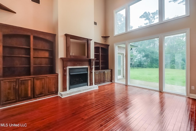 unfurnished living room with a towering ceiling and hardwood / wood-style floors