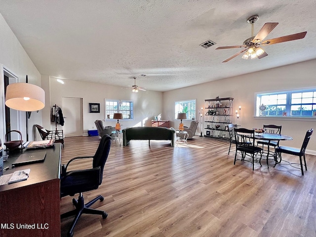 interior space featuring a textured ceiling, wood finished floors, a ceiling fan, and baseboards