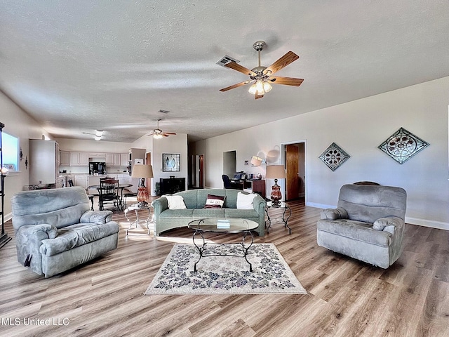 living area with light wood-style floors, visible vents, and a textured ceiling