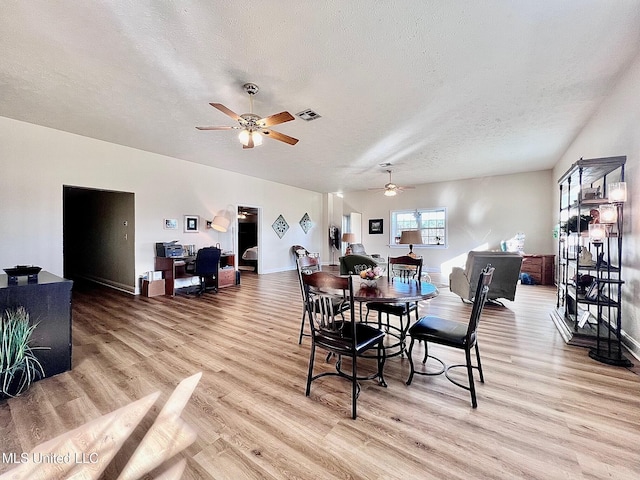 dining space featuring visible vents, light wood-style floors, ceiling fan, a textured ceiling, and baseboards