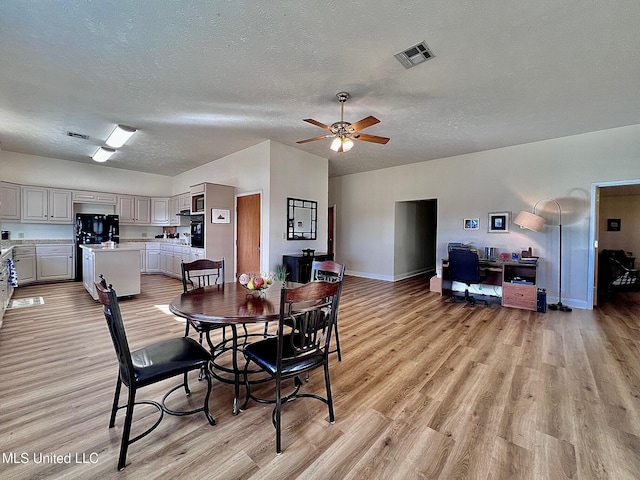 dining area with light wood-style floors, visible vents, and a textured ceiling