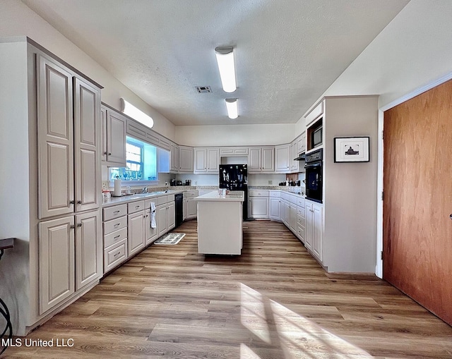 kitchen with visible vents, light countertops, light wood-style flooring, a kitchen island, and black appliances